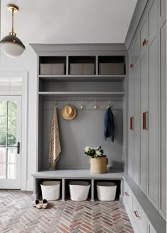 an entryway with built - in storage and baskets on the floor, along with several coat racks