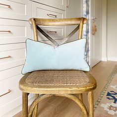 a wooden chair with a blue pillow on top of it next to a white cabinet