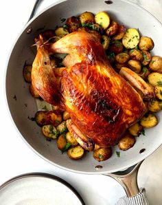 a roasted chicken and potatoes in a pan