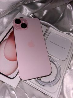 two pink iphones sitting on top of each other next to an apple phone charger