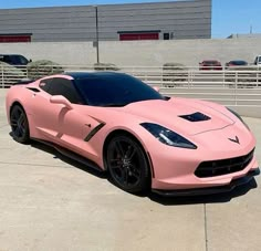 a pink sports car parked in front of a building