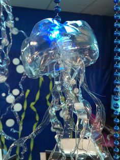 a glass figurine is displayed in front of a blue background with bubbles and beads