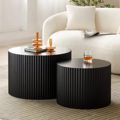 two black tables sitting on top of a rug in front of a white couch and coffee table