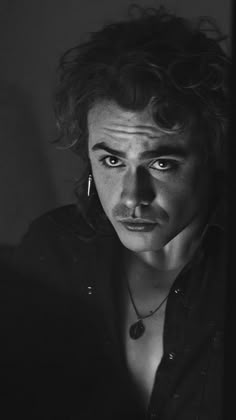 a black and white photo of a young man with curly hair looking at the camera