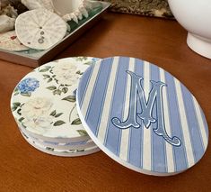 three coasters with the letter m on them sitting on a table next to other plates