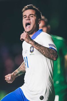 a soccer player with his mouth open and one hand in the air as he celebrates