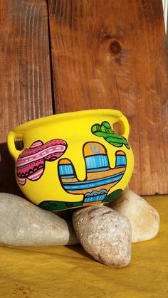 a yellow bowl sitting on top of a wooden table next to two rocks and a rock