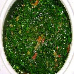 a white bowl filled with green vegetables on top of a table