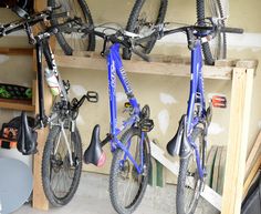 two bikes are hanging on the wall in a bike storage area with shelves and tools