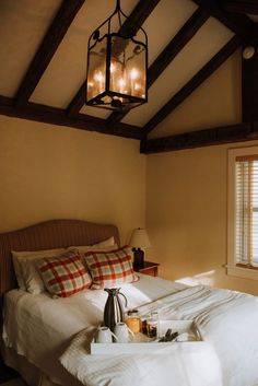 a bed sitting under a light in a bedroom next to a window with two lamps on top of it