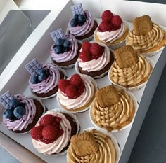 a box filled with cupcakes covered in frosting and fruit