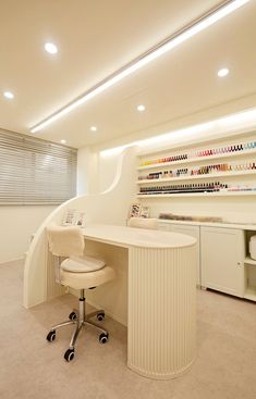 a room with a desk, chair and shelves full of nail polishes on the wall