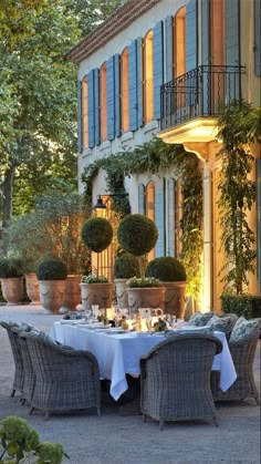 an outdoor dining area with potted plants on the outside wall and table set for four