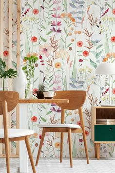 the wallpaper in this dining room is painted with colorful flowers and leaves, as well as two wooden chairs