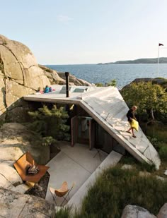 a child is standing on the roof of a house by the water's edge