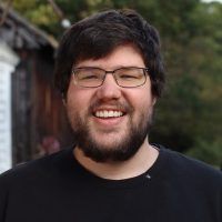 a man with glasses is smiling for the camera while wearing a black t - shirt