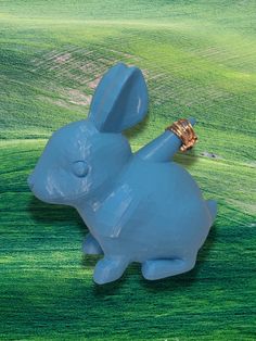 a blue rabbit statue laying on top of a green field