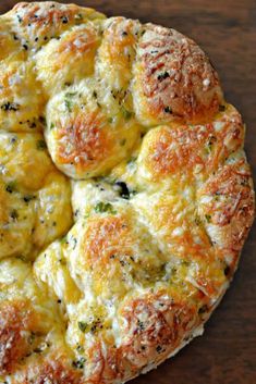 a cheesy bread with cheese and herbs on it sitting on a wooden table