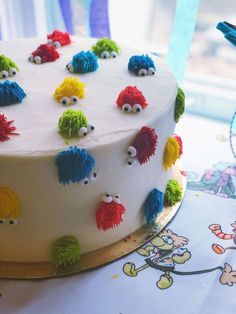 a white cake with colorful frosting and eyes on it's side sitting on top of a table