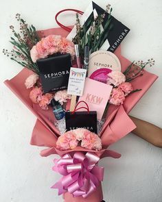 a bouquet of pink flowers and personal items is held by a woman's hand