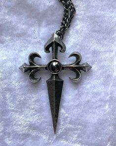 The charge of the 12th century Spanish knights, The Order of St. James of the Sword, vowed to protect pilgrims and extirpate infidels. An antiqued pewter cross pendant in a traditional style, raised in relief with fleur-de-lys ends to the arms of the cross and a sword-pointed shaft, and a dark, round hematite cabochon at its centre. The pendant comes with a velvet gift pouch. Made by Kiss of a red rose with help from Alchemy England 1977.