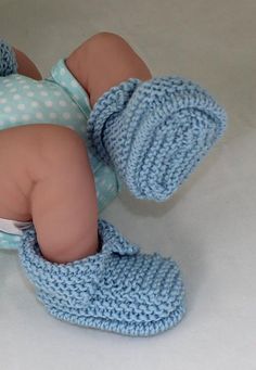 a baby doll with blue knitted clothes and booties