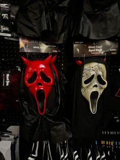 two masks with red and black faces are hanging on the wall next to each other