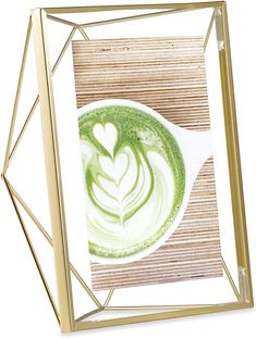 a cup of green liquid in a gold frame