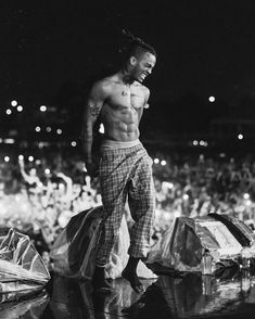 a shirtless man standing on top of a pile of bags in front of a crowd