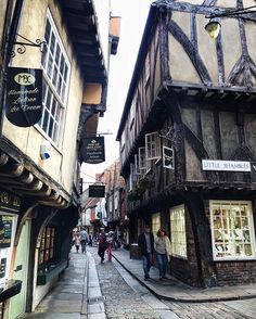 people are walking down the narrow street in an old european town with half - timbered buildings