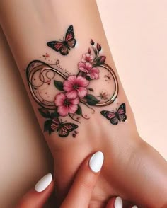 a woman's arm with flowers and butterflies on it, while she is holding the wrist