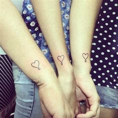 two people holding hands with hearts tattooed on their arms and the other hand behind them