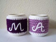 two crocheted mugs with the letters m and a on them are sitting next to each other