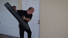 a man holding a large black object in front of a door