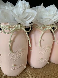 four pink mason jars with white flowers in them are sitting on a burlock