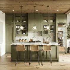 a kitchen with green cabinets and marble counter tops, two bar stools in front of the island