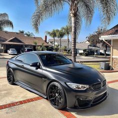 a black car parked in front of a palm tree