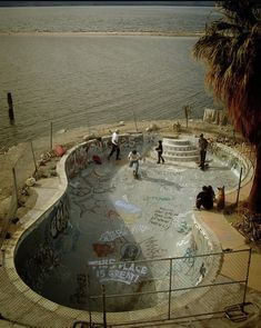 skateboarders in an empty swimming pool with graffiti on the walls