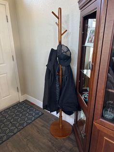 a coat rack with an umbrella and jacket hanging from it's top, next to a door