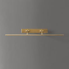 two brass - plated hooks hang on a gray wall