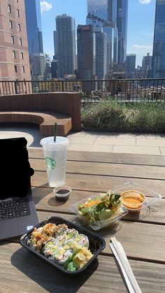 an open laptop computer sitting on top of a wooden table next to a plate of food