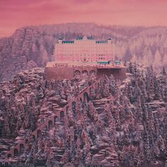 a large building sitting on top of a mountain covered in snow next to evergreen trees