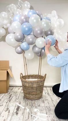 a woman sitting on the floor with balloons in front of her and a basket full of them