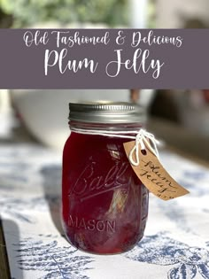 a mason jar filled with plum jelly sitting on top of a blue and white table cloth