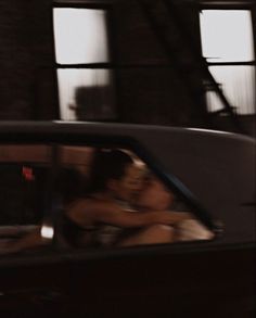 a man and woman are kissing in the back seat of a car while another person is driving behind them