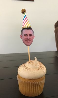 a cupcake with a photo of a man's face on it, sitting on a table