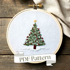 a cross stitch christmas tree on a wooden background with the words pdf pattern below it