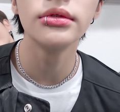 a person wearing a black jacket with a chain around their neck and nose piercings