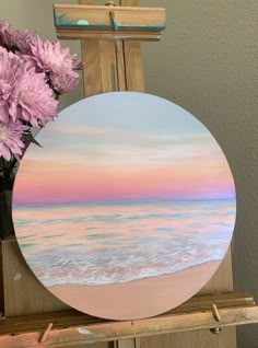 a vase with pink flowers sitting on top of a wooden easel