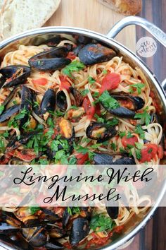 linguinne with mussels in a pan on a wooden table next to bread